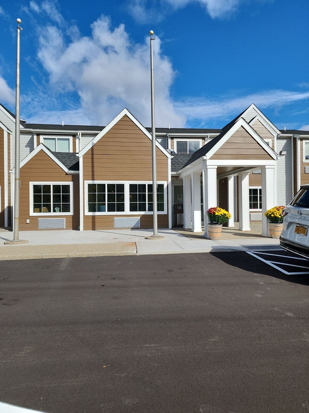 Modern building with brown siding, large windows, and colorful flower pots at the entrance.
