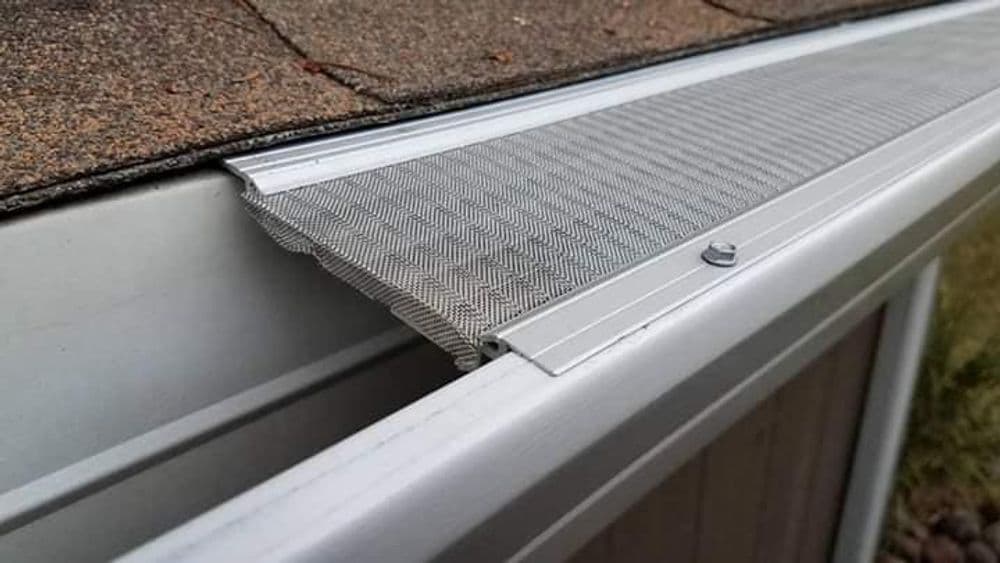 Roof drip edge with metal flashing and textured gutter screen on shingles.