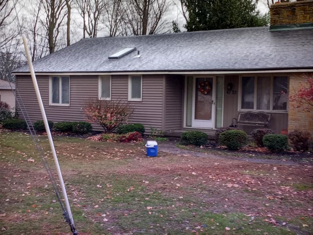 Front view of a single-story house with a gray roof and seasonal decorations in the yard.