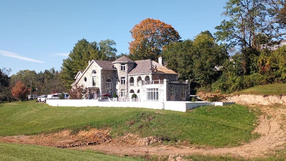 Historic stone mansion surrounded by lush greenery and clear blue skies. Perfect for real estate.