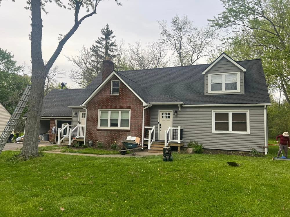 Charming two-story home with a mix of brick and siding, surrounded by green grass and trees.