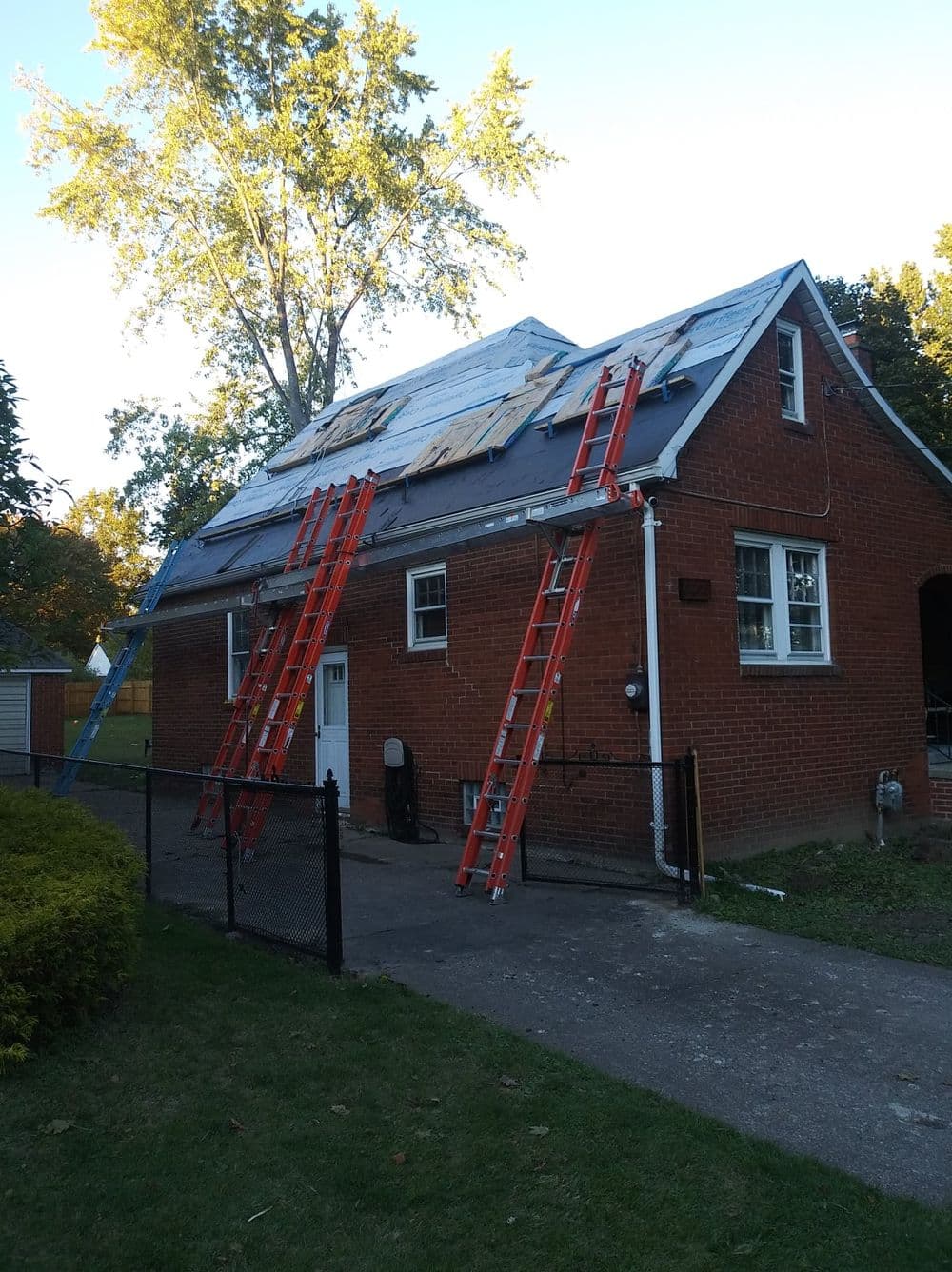 House under renovation with ladders and solar panels being installed on the roof.