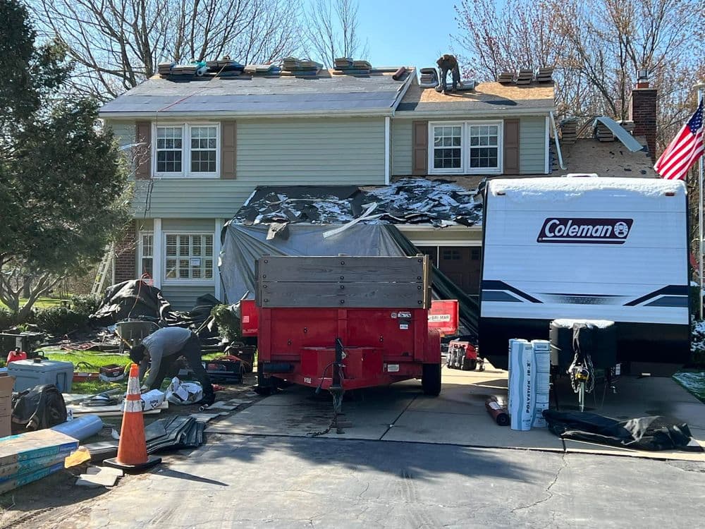Home renovation with roofing work underway, truck and equipment in front yard.