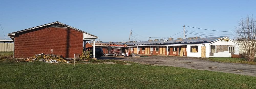 Abandoned motel with renovations underway, featuring a red brick building and fire truck.