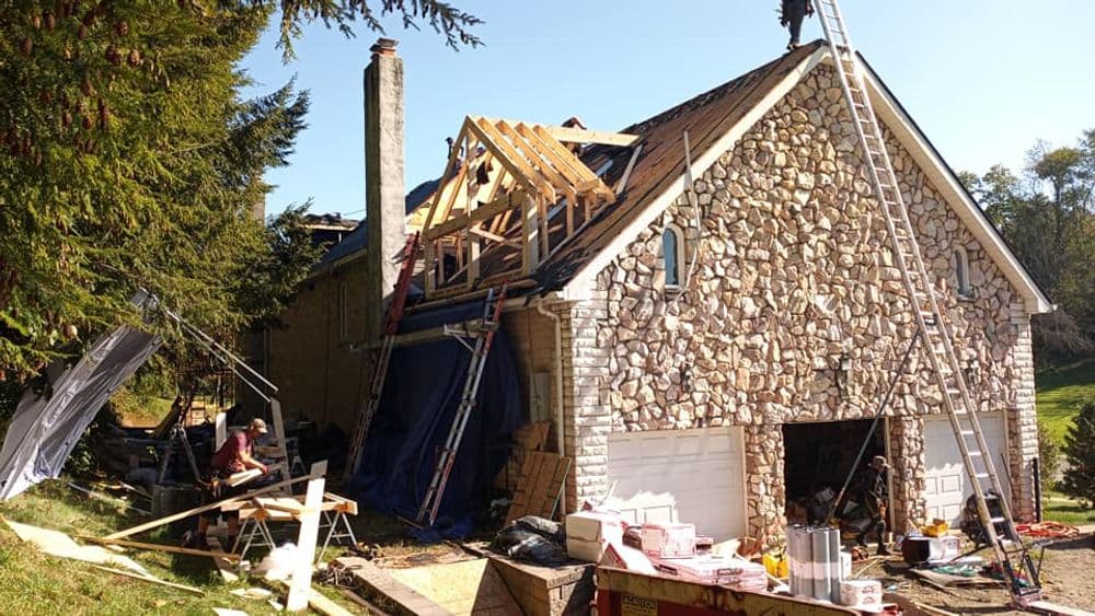 Home renovation in progress with exposed roof and construction materials outside.