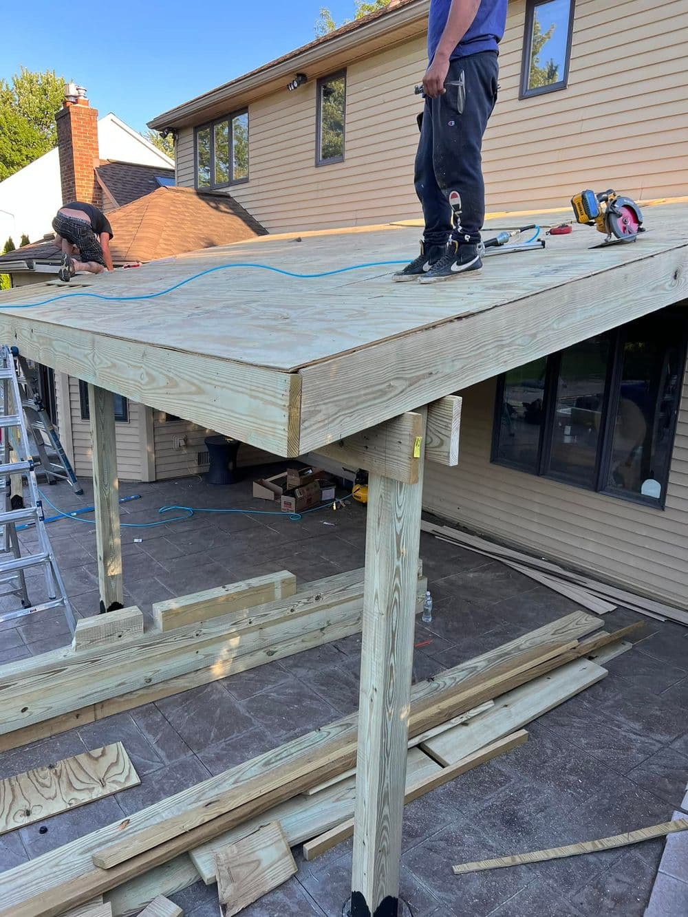 Construction workers building a wooden deck extension on a home's exterior.